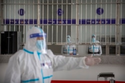 រូបឯកសារ៖ មន្ត្រីសន្តិសុខចិនក្នុងឯកសណ្ឋានការពារការឆ្លងមេរោគ បង្ហាញផ្លូវដល់អ្នកធ្វើទស្សនកិច្ចក្នុងមជ្ឈមណ្ឌលឃុំឃាំង Urumqui លេខ ៣ ក្នុងសង្កាត់ Dabancheng ភាគខាងលិចនៃតំបន់ Xinjiang ដែលសំបូរដោយជនជាតិភាគតិច Uyghur រស់នៅ ថ្ងៃទី ២៣ ខែមេសា ឆ្នាំ ២០២១។