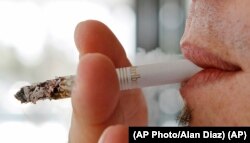 In this photo taken Monday, Feb. 7, 2011, a person smoking a Marlboro cigarette.