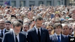 King Felipe of Spain, center, Prime Minister Mariano Rajoy, center left, and Catalonia regional President Carles Puigdemont, center right, join people gathered for a minute of silence in memory of the terrorist attacks victims in Barcelona, Spain.