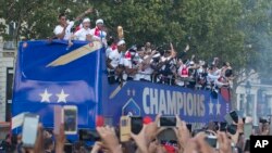 Well-wishers cheer the victorious French team parading aboard a bus on the famed Champs Elysees avenue in Paris, France, after their 4-2 victory Sunday over Croatia to capture the trophy in the final of the FIFA World Cup, Monday, July 16, 2018. (AP Photo