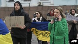 Familiares y amigos de prisioneros de guerra ucranianos de la Brigada Azov y subunidades sostienen pancartas y la bandera ucraniana durante una manifestación frente al edificio de la Ópera en Kiev el 17 de marzo de 2024, pidiendo su intercambio con prisioneros rusos. [Foto:AFP]