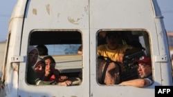 Displaced Palestinians sit alongside their belongings in a van driving in al-Bureij camp in the central Gaza Strip on June 2, 2024.
