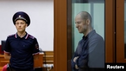 Wall Street Journal reporter Evan Gershkovich, who stands trial on spying charges, reacts inside an enclosure for defendants before a court hearing in Yekaterinburg, Russia June 26, 2024. 