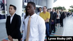 Luis Mendez, left, a student at Miami Dade College, left, and Maurice Mike, a student at Florida International University, wait in line at a job fair held by the Miami Marlins baseball team, at Marlins Park in Miami, Florida in 2013.
