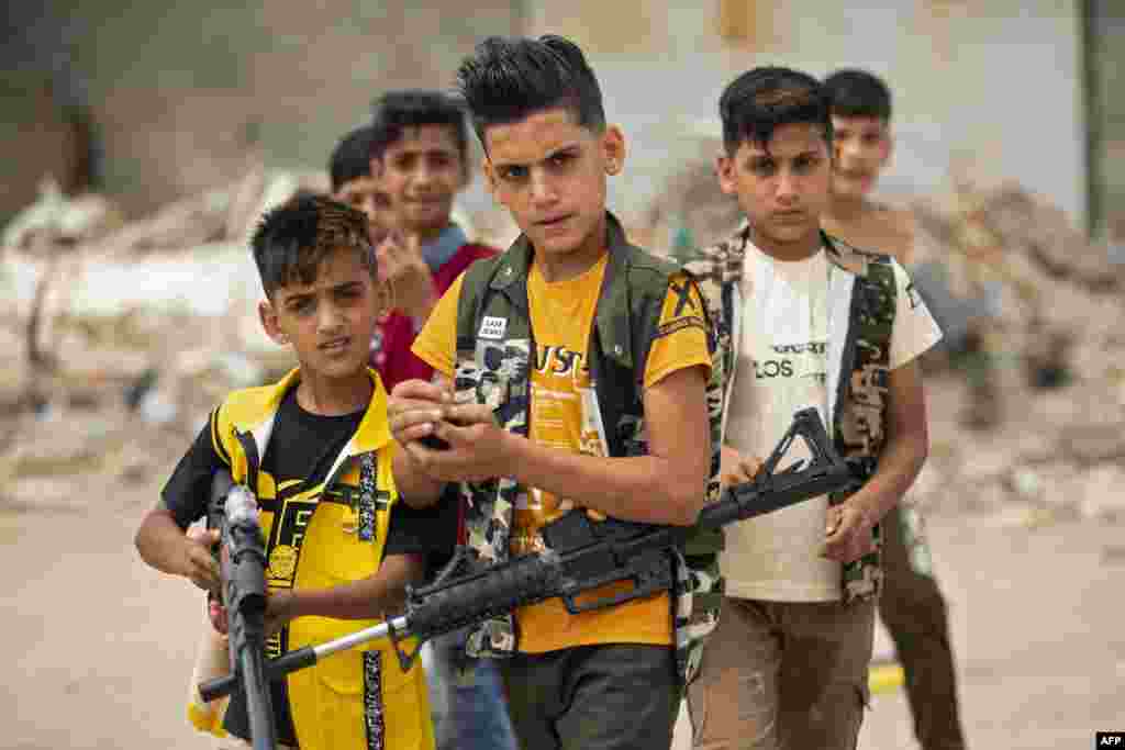 Iraqi children play with plastic toy guns as they celebrate Eid al-Fitr, the Muslim holiday which starts at the conclusion of the holy fasting month of Ramadan, in the southern Iraqi city of Basra.