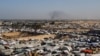 Una vista general de un campamento de tiendas de campaña que alberga a palestinos desplazados, mientras el humo se eleva en la distancia debido a una operación terrestre israelí en Khan Younis, en el sur de la Franja de Gaza, el 22 de enero.
