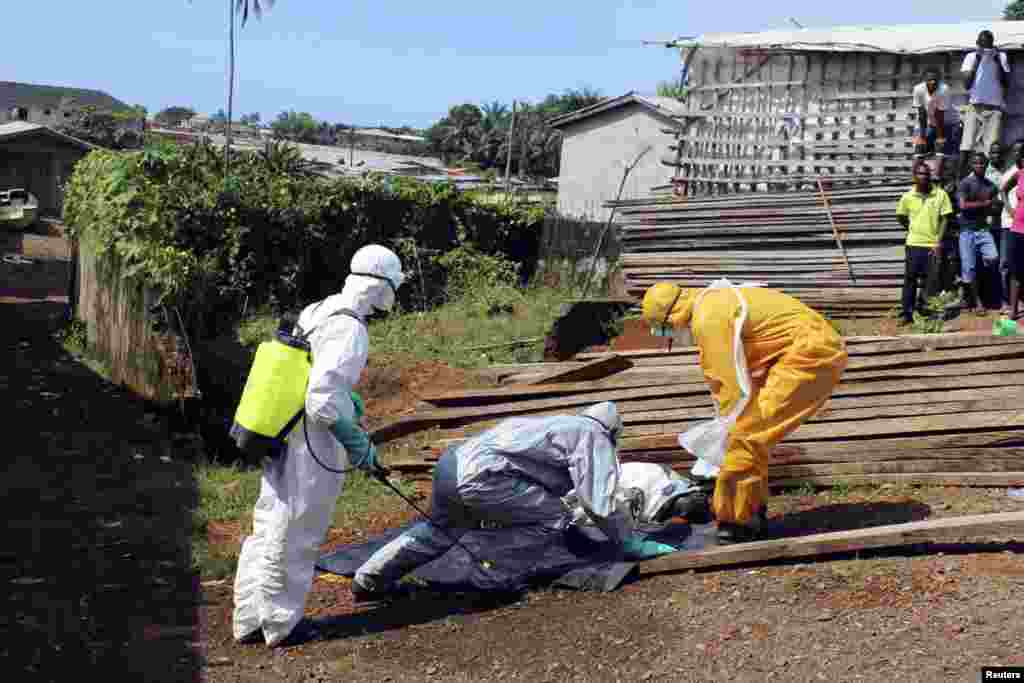 Health workers remove the body a woman who died from the Ebola virus in the Aberdeen district of Freetown, Sierra Leone, Oct. 14, 2014. 