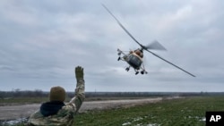 Un soldado ucraniano saluda a un helicóptero militar que regresa del combate, cerca del frente en la región de Kherson, Ucrania, el domingo 8 de enero de 2023. (Foto AP/LIBKOS)