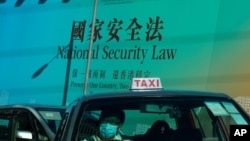 រូបឯកសារ៖ រថយន្ត​តាក់ស៊ី​បើក​កាត់​បដា​ធំ​មួយ​ដែល​មាន​សំណេរ​ថា ច្បាប់​សន្តិសុខ​ជាតិ​សម្រាប់​ហុងកុង នៅ​ក្នុង​ទីក្រុង​ហុងកុង នៅ​ថ្ងៃទី២៩ ខែមិថុនា ឆ្នាំ២០២០។