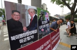FILE - A photo showing U.S. President Donald Trump and North Korean leader Kim Jong Un is displayed as a member of the People's Democratic Party stands to oppose military exercises between the United States and South Korea near the U.S. embassy in Seoul, South Korea, June 19, 2018.