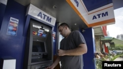 ၂၀၁၂ ခုနှစ်၊ နိုဝင်ဘာ ၁၅ ရက်က ရန်ကုန်မြို့မှာ ATM စက်ကနေ MasterCard ကတ်နဲ့ ငွေသားထုတ်ယူနေတဲ့ အမေရိကန်နိုင်ငံသားတဦး။ (ယခင်မှတ်တမ်းဓာတ်ပုံ) 