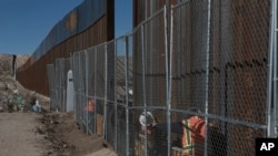 Workers continue work raising a taller fence in the Mexico-US border separating the towns of Anapra, Mexico and Sunland Park, New Mexico, Jan. 25, 2017.