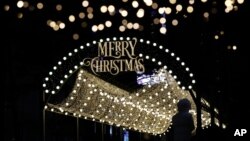 Žena sa maskom na licu tokom pandemije koronavirusa fotografiše božićnu dekoraciju u Seulu, Južna Koreja, 24. deembra 2020. (AP Photo/Lee Jin-man)