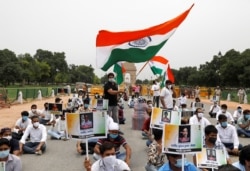 FILE - A police officer heckles a supporter of India's main opposition Congress party as others pay tribute to the Indian army soldiers killed in a border clash with Chinese troops in Ladakh region, at India Gate, in New Delhi.