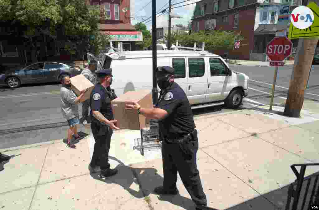 Oficiales de policía ayudan al pastor Carmelo Ureña a bajar y repartir donaciones para la comunidad de Camden, Nueva Jersey.