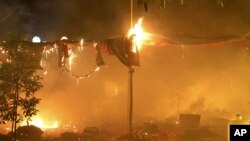 FILE - In this photo released by Eleven Media Group, an encampment occupied by protesters burns at the Letpadaung mine following a crackdown by security forces, near the town of Monywa, early Thursday morning, November 29, 2012.