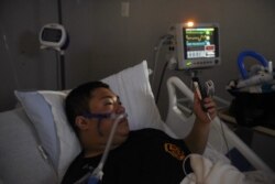 Duc Nguyen akaiongea na mkewe kupitia FaceTime siku ya Mwaka Mpya akiwa katika wodi ya virusi vya corona katika kituo cha afya cha United Memorial, Houston, Texas, Marekani, Jan. 1, 2021.