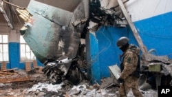 ទាហាន​អ៊ុយក្រែន​ម្នាក់​ដើរ​កាត់​បំណែក​កន្ទុយ​យន្តហោះ​បាញ់​គ្រាប់បែក​រុស្ស៊ី Su-34 ដែល​នៅ​ជាប់​នៅ​ក្នុង​អគារ​ខ្ទេចខ្ទាំ​មួយ​នៅ​ទី​ក្រុង Kharkiv ប្រទេស​អ៊ុយក្រែន កាល​ពី​ថ្ងៃ​អង្គារ​ទី​៨ ខែ​មីនា ឆ្នាំ​២០២២។ (AP)