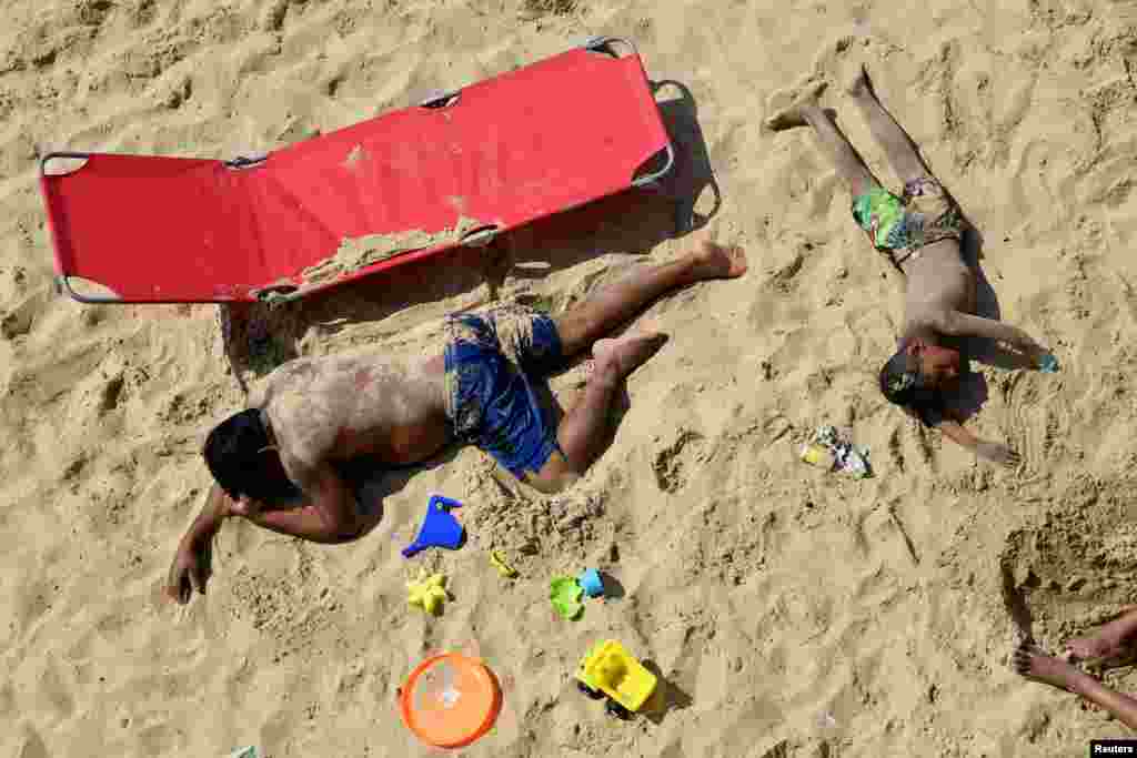 People rest at the Bournemouth Beach, on what is one of Britain's hottest days of the year so far, amid the coronavirus disease outbreak, in Bournemouth, Britain.