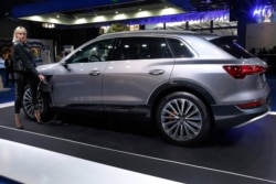 FILE - A model holds the power cable that charges the new electric Audi e-tron Quatro, displayed at the e-Motor show in Beirut, Lebanon, April 11, 2019.