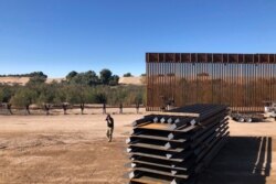 FILE - People work at a portion of border wall under construction in Yuma, Arizona, Jan. 10, 2020.