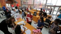 រូប​​ឯកសារ៖ ក្រុម​អ្នក​ស្វែង​រក​ការងារ​កំពុង​បំពេញ​ទម្រង់​ពាក្យ​សុំការងារ​ក្នុង​ពិព័រណ៍​ការងារ​មួយ​នៅ​ទីក្រុង​ Miami រដ្ឋ Florida កាល​ពី​ឆ្នាំ​កន្លង​ទៅ។