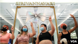 មេដឹកនាំបាតុកម្មពាក់អាវចេញក្បាលពោះនិងបង្ហាញស្នាមញញឹម និងម្រាមដៃបីដាក់នៅមុខហាងលក់សំលៀកបំពាក់ «ម្ចាស់ក្សត្រីថៃ Sirivannavari» នៅឯផ្សារទំនើប Siam Paragon ខណៈពួកគេតវ៉ាប្រឆាំងនឹងរាជានិយមនៅទីក្រុងបាងកកថ្ងៃទី ២០ ខែធ្នូឆ្នាំ ២០២០។ (Reuters)