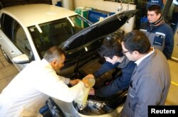 Biochemist Cesar Saez (L) does a test on the engine of a car with a biofuel made with microalgae for high displacement diesel engines for reducing emissions of gases and particulate matter in Santiago, Chile, June 28, 2017.