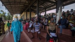 រូបឯកសារ៖ ទាហាន​ស្រីលង្កា​ម្នាក់​ក្នុង​ឯកសណ្ឋាន​ការពារ​ពី​ជំងឺ​កូវីដ១៩ ដើរ​កាត់​ប្រជាជន​ដែល​រង់ចាំ​ចាក់​វ៉ាក់សាំង​បង្ការ​ជំងឺ​កូវីដ១៩​ស៊ីណូហ្វាម​របស់​ចិន​នៅ​មជ្ឈមណ្ឌល​ចាក់​វ៉ាក់សាំង​មួយ​ក្នុង​ទីក្រុង​កូឡុំបូ ប្រទេស​ស្រីលង្កា ថ្ងៃទី១១ ខែឧសភា ឆ្នាំ២០២១។