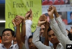 Members of the opposition Cambodia National Rescue Party raise joined hands for photographs at their party headquarters in Phnom Penh, May 27, 2016. A Cambodian court had convicted three military commandos of beating up two CNRP lawmakers outside the parliament in the previous year and had sentenced them to one year each in prison.