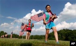 FILE - Girl Scouts place flags on veterans' graves at Brig. Gen. William C. Doyle Veterans Memorial Cemetery in Wrightstown, N.J., in honor of Memorial Day, May 27, 2016.