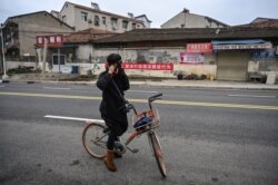 A woman puts a protective mask in a neighborhood on the outskirts of Wuhan in China's central Hubei province on January 27, 2020, amid a deadly virus outbreak which began in the city.