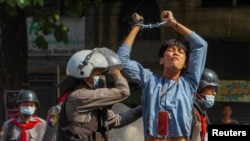 FILE - A pro-democracy protester is detained by riot police during a rally against the military coup in Yangon, Myanmar, Feb. 27, 2021.