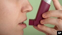 FILE - A person uses an inhaler to cope with asthma.