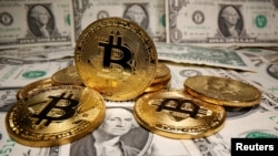FILE - Representations of virtual currency Bitcoin are placed on U.S. Dollar banknotes in this illustration taken May 26, 2020.