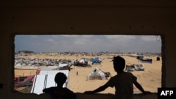 Anak-anak Palestina mengamati kamp untuk pengungsi di Rafah, bagian selatan Jalur Gaza yang berbatasan dengan Mesir di tengah perang antara Israel dan kelompok Hamas Palestina, 28 April 2024. (Foto: AFP)