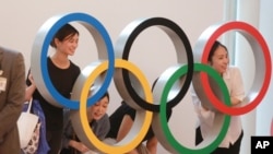 People pose for photo with the Olympics Rings display at Haneda International Airport in Tokyo, July 8, 2021.