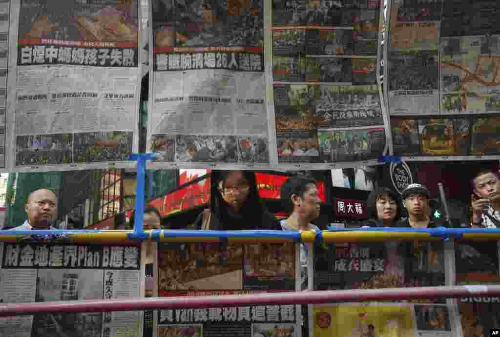 Visitors view the latest newspaper coverage of clashes between protesters and police at a sit-in protest in Hong Kong, Sept. 29, 2014. 