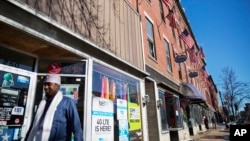 FILE - U.S. flags hang outside a downtown building whose storefronts are made up of businesses started by African immigrants who have settled in Lewiston, Maine, March 17, 2017. Maine's immigrants from Sub-Saharan Africa made $136.6 million in income in 2014, and paid $40 million in taxes, according to a report from the New American Economy, a bi-partisan coalition pushing for immigration reform. 