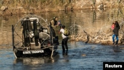 Una familia migrante es recogida por un miembro del Departamento de Seguridad Pública de Texas después de quedar varada en la orilla del río durante horas, en Eagle Pass, Texas, el 18 de enero de 2024.