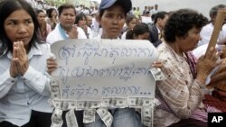 A Cambodian supporter holds a banner reading: "The court system must be respected by the public not for..." as she sits with other supporters of Mam Sonando, one of Cambodia’s most prominent human rights defenders, in front of Phnom Penh Municipal Court in Phnom Penh, Cambodia, Tuesday, Sept. 11, 2012. Some 300 supporters gathered for prayer for local radio station owner Sonando, who has been held in pre-trial detention for almost two months for insurrection charge, during his court appearance. (AP Photo/Heng Sinith)