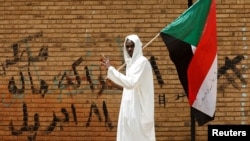 Sudan bayrog'ini ko'tarib olgan namoyishchi, Xartum, Sudan, 2019-yil, 19-aprel
