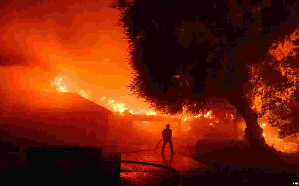 A firefighter works at the scene as dozens of homes continue to burn during the Eaton Fire in the Altadena area of Los Angeles County, California, Jan. 8, 2025.