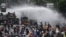 Police officers spray water using a canon to disperse demonstrators during a protest against the government's labour reforms in a polarising jobs creation bill in Jakarta
