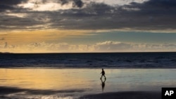 A person walks on Orewa Beach in Auckland, New Zealand, on June 5, 2021. New Zealand has recorded its warmest June since recordkeeping began, as ski fields struggle to open and experts predict shorter southern winters in the future. (Brett Phibbs/New Zealand Herald via AP)