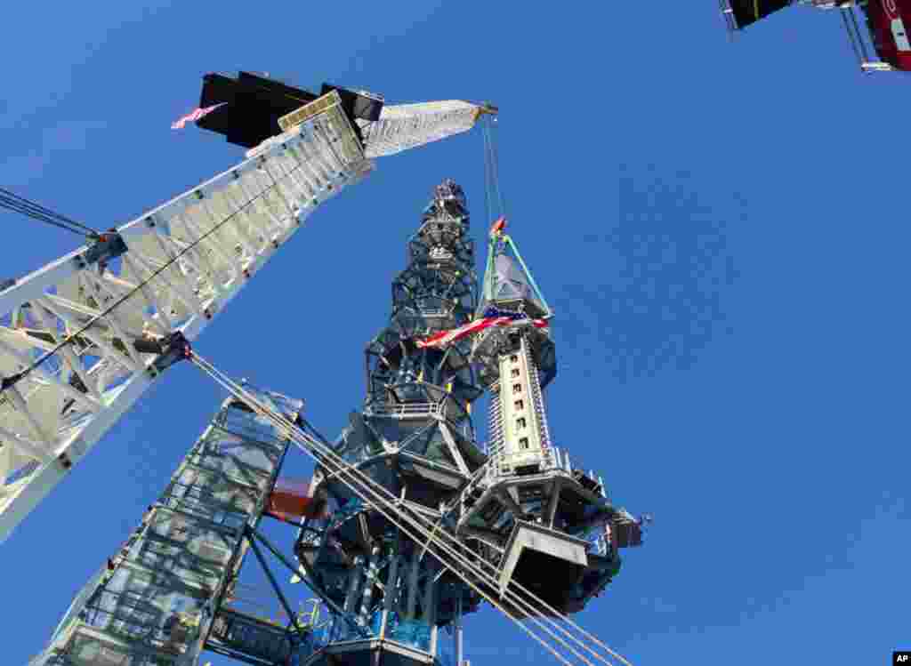 The silver spire topping One World Trade Center is lifted as it is fully installed on the building's roof, bringing the structure to its full, symbolic height of 1,776 feet (541 meters), May 10, 2013 in New York.