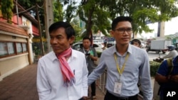 In this photo taken on Oct. 3, 2019, journalists Uon Chhin, left, and Yeang Sothearin arrive at the municipal court, in Phnom Penh. A Cambodian court has ordered a new investigation and postponed a verdict in the espionage trial of the two journalists.
