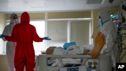 Medics wearing protective suits consult as they treat a COVID-19 patient in intensive care at the Moscow City Clinical Hospital 52, in Moscow, Russia, Oct. 19, 2021.
