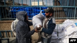 Palestinos desplazados reciben ayuda alimentaria en la sede de UNRWA en Rafah, en el sur de la Franja de Gaza, el 28 de enero de 2024. La agencia de asistencia de la ONU se encuentra actualmente en el ojo de la tormenta.