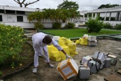 FILE - A lab technician at the Pasteur Institute of Ivory Coast looks at collected samples to be tested for the coronavirus and other samples for analysis, near Abidjan, May 11, 2020.